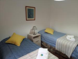 Habitación con 2 camas y mesa con lámpara. en La casita de mi infancia en Mendoza