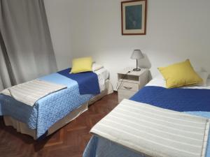 1 dormitorio con 2 camas y mesita de noche con lámpara en La casita de mi infancia en Mendoza