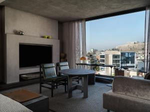 een woonkamer met een televisie en een tafel en stoelen bij Monastik Living in Athina in Athene