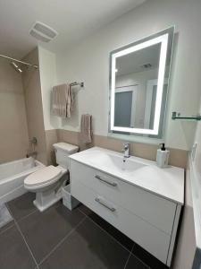 a bathroom with a sink and a toilet and a mirror at Modern Loft in DTLA - Rooftop Pool & Free Parking! in Los Angeles
