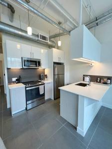 a kitchen with white cabinets and a stove top oven at Modern Loft in DTLA - Rooftop Pool & Free Parking! in Los Angeles