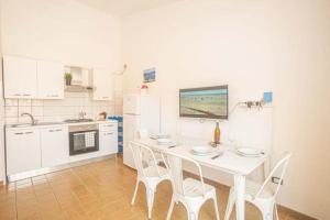 a white kitchen with a white table and chairs at Fortuna in Campese