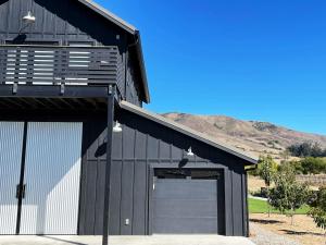 a black barn with a garage door and mountains in the background at Black Barn Ranch Hill Views Downtown Close in San Luis Obispo