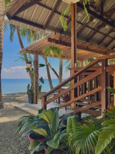 a wooden pavilion on the beach with the ocean at Inay’s Beachfront House in San Juan