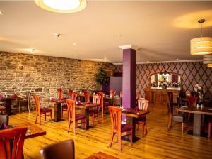 a restaurant with wooden tables and chairs and a brick wall at Royal Hotel in Forfar