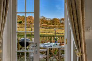 een kamer met een tafel en uitzicht op een veld door een raam bij Garden flat near Goodwood with stunning views in Petersfield