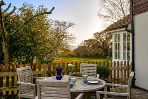 een tafel en stoelen op een patio met een hek bij Garden flat near Goodwood with stunning views in Petersfield