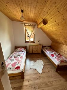 two beds in a room with a wooden ceiling at Zrub Vlašky in Bešeňová