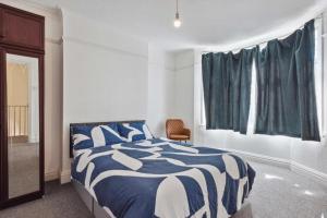 a bedroom with a blue and white bed and a window at Cozy Stay Rooms in Raynes Park