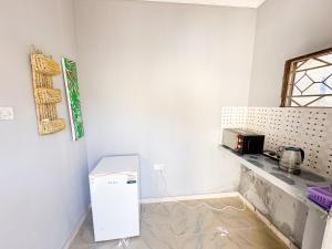 een keuken met een witte koelkast en een aanrecht bij Mama's House in Kibweni