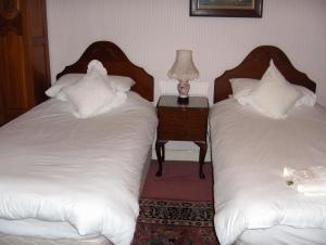 dwa łóżka w pokoju ze stołem i lampką w obiekcie The Old School House Mordington w mieście Mordington