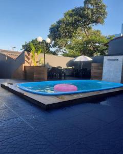 a swimming pool with a table and an umbrella at Segundo andar in Uberlândia