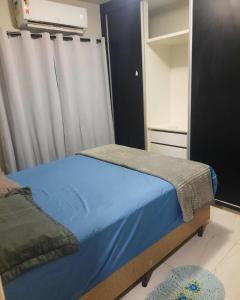 um quarto com uma cama com lençóis azuis e uma janela em Segundo andar em Uberlândia