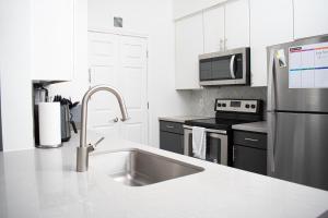 a white kitchen with a sink and a refrigerator at Midtown Contemporary Luxury 1BD-Pool-Gym-Patio-Office in Houston