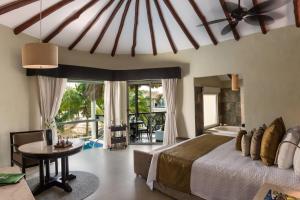 a bedroom with a bed and a table and a room at El Dorado Casitas Royale Catamarán, Cenote & More Inclusive in Puerto Morelos