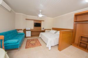 1 dormitorio con 1 cama y 1 sofá azul en Hotel Cozumel Sierra en Canela