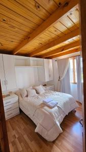 uma cama grande num quarto com tecto em madeira em La casita suereña em Esquel