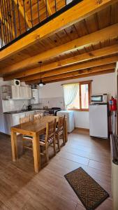 uma cozinha e sala de jantar com uma mesa de madeira e cadeiras em La casita suereña em Esquel