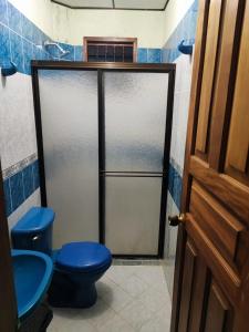 a bathroom with a blue toilet and a glass door at Hostal La Pola in Santa Fe de Antioquia