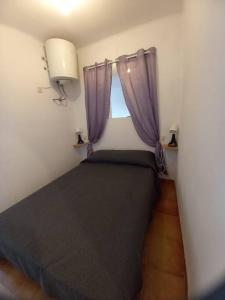 1 dormitorio con 1 cama con cortinas moradas y ventana en Bonito apartamento vista mar, en Empuriabrava
