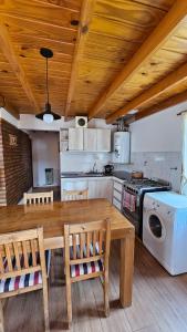 uma cozinha com uma mesa e cadeiras de madeira e um fogão em La casita suereña em Esquel