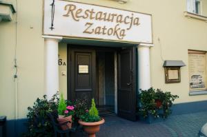 uma entrada de restaurante com vasos de plantas em frente a um edifício em ''Zatoka" em Bydgoszcz