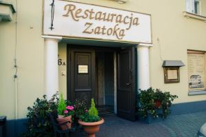 a restaurant entrance with pots of plants in front of a building at ''Zatoka" in Bydgoszcz