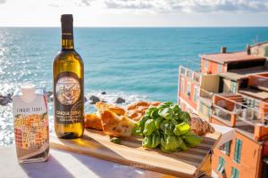 Alla Marina Affittacamere في ريوماجّوري: زجاجة من النبيذ وصحن من الطعام بجوار المحيط