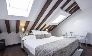 a bedroom with a large white bed and wooden ceilings at Hospes Puerta de Alcalá, a Member of Design Hotels in Madrid