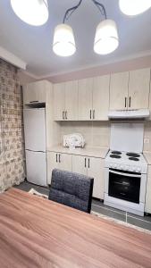 a kitchen with white cabinets and a stove and a chair at 3 комнатная квартира Бесагаш Сити in Almaty