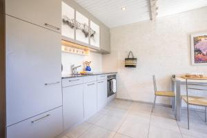 een keuken met witte kasten en een tafel bij Dom Apartment in Riederalp