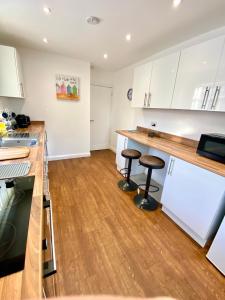 a kitchen with wooden floors and white cabinets and stools at Eden Stay in Morecambe