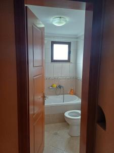 La salle de bains est pourvue de toilettes et d'une baignoire. dans l'établissement Leonidas Apartment, à Berat