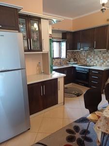 La cuisine est équipée d'un réfrigérateur blanc et de placards en bois. dans l'établissement Leonidas Apartment, à Berat
