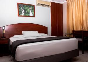 a bedroom with a large bed with a wooden headboard at Grand Hotel Machala in Machala