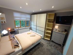 a bedroom with a large bed and a television at Lovely room with ensuite in a quiet house in Rayleigh