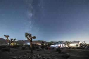 a starry sky with palm trees and a building at New: Dome, Hot Tub, Game Room, 5 min to park in Joshua Tree
