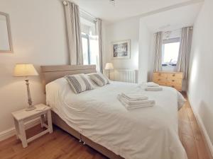 a bedroom with a white bed with towels on it at TULLOCHSIDE-4 BED-SEA FRONT -RAVENSPOINT ROAD in Trearddur