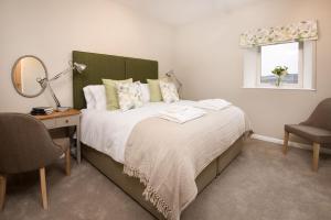 1 dormitorio con 1 cama con espejo y silla en Byre en Melrose