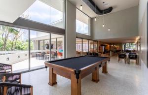 a pool table in the middle of a room with windows at Studio aeroporto Congonhas in São Paulo