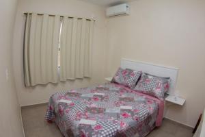 a bedroom with a bed with a quilt on it at Apartamento encantador próximo praia mercado Farm padaria in Imbituba