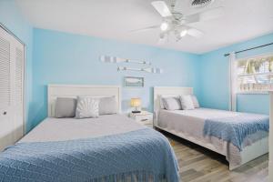 um quarto azul com 2 camas e uma ventoinha de tecto em Boat Lovers Paradise Walk to Private Beach! em Jensen Beach