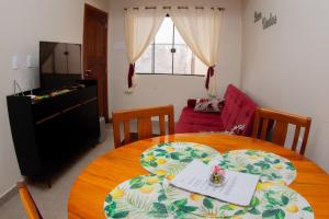 a dining room with a table and a living room at Apartamento encantador próximo praia mercado Farm padaria in Imbituba