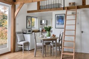 uma cozinha com mesa e cadeiras e uma cama alta em Stunning Cabin with incredible views near Goodwood em Rogate