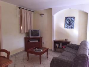sala de estar con sofá y TV en Borgo dei Conti Holiday Home, en Capitana