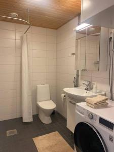 a bathroom with a toilet sink and a washing machine at Parvekkeellinen moderni asunto in Turku