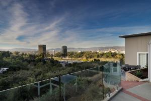 uma varanda de vidro com vista para a cidade em Luxury Hollywood Hills Gated VIEW estate - ultra private and gorgeous! MINUTES TO UNIVERSAL STUDIOS AND HOLLYWOOD! em Los Angeles