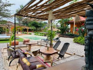 een patio met een tafel en stoelen en een parasol bij CAJOU LODGE in Bubaque