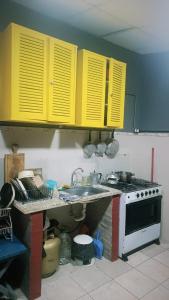 a kitchen with yellow cabinets and a stove at Posada the secret in Colonia del Sacramento