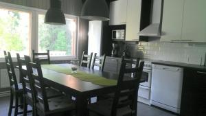 a kitchen with a wooden table with chairs and a table and a window at Metsäniityn Tuvat in Billnäs
